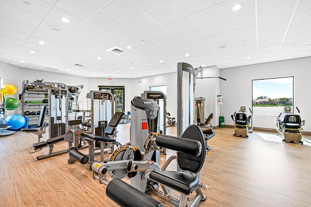 gym with a drop ceiling and light hardwood / wood-style floors