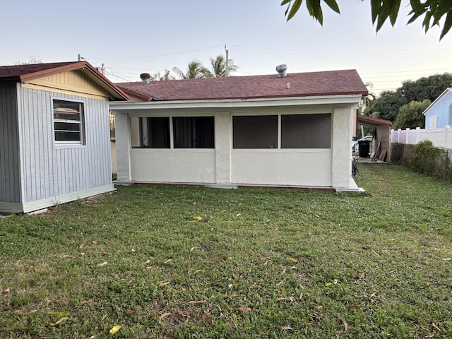 rear view of house featuring a yard and a sunroom