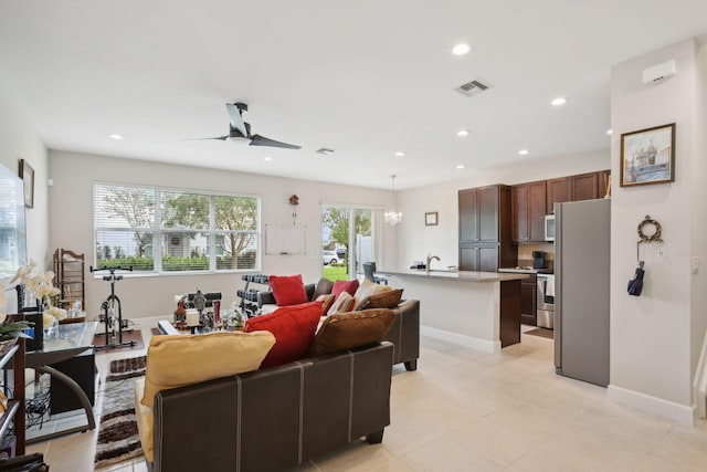 living room with sink and ceiling fan with notable chandelier