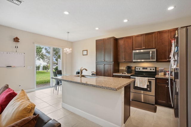 kitchen with appliances with stainless steel finishes, a kitchen island with sink, sink, a notable chandelier, and hanging light fixtures