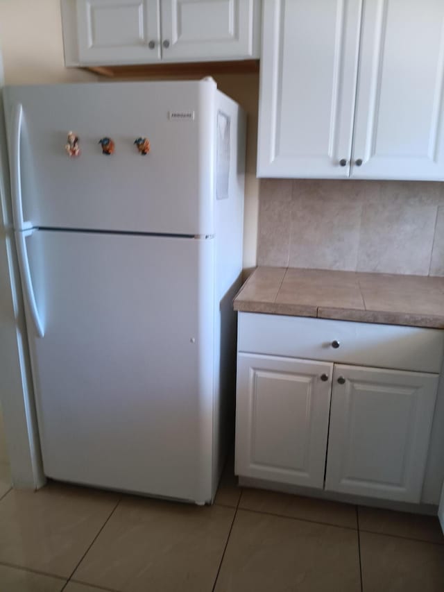 kitchen with white cabinets, white fridge, and light tile patterned floors