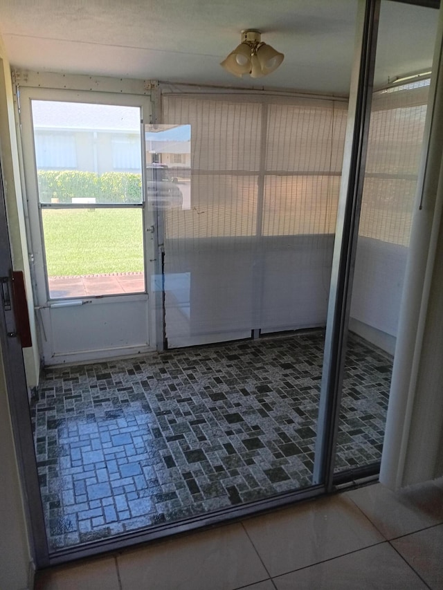 doorway to outside with dark tile patterned flooring