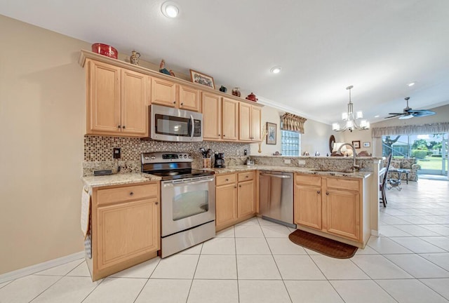 kitchen featuring backsplash, ceiling fan with notable chandelier, sink, kitchen peninsula, and stainless steel appliances