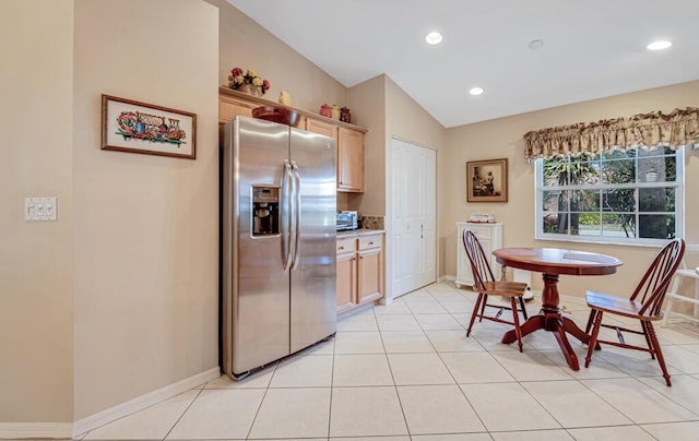 kitchen featuring lofted ceiling, light brown cabinetry, light tile patterned floors, and stainless steel refrigerator with ice dispenser