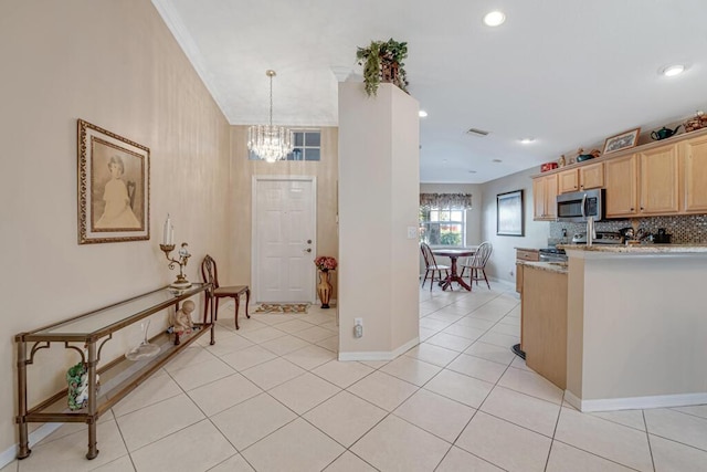 kitchen with light stone countertops, light brown cabinets, light tile patterned flooring, and hanging light fixtures