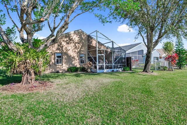 rear view of house featuring a lanai and a yard