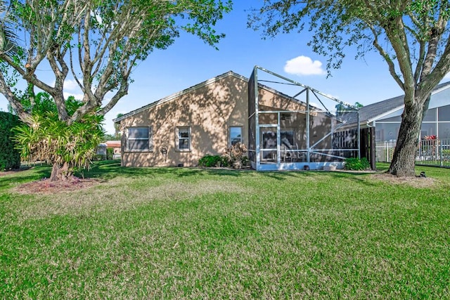 rear view of house with a lawn and a lanai