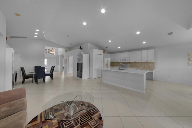 living room featuring sink, light tile patterned floors, and lofted ceiling