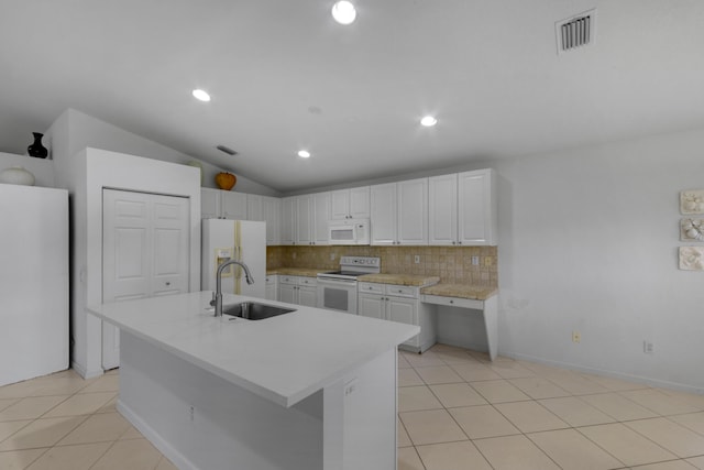 kitchen with white appliances, white cabinets, sink, a kitchen island with sink, and vaulted ceiling