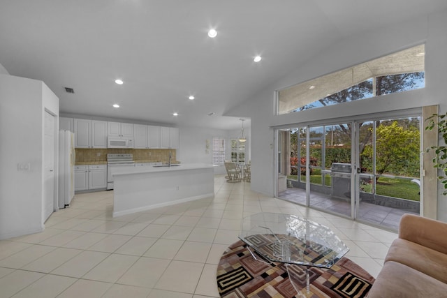 kitchen featuring white appliances, white cabinets, an island with sink, decorative backsplash, and sink