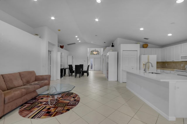 living room with light tile patterned floors, vaulted ceiling, and sink