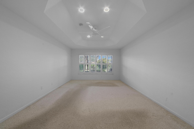 carpeted spare room featuring a tray ceiling