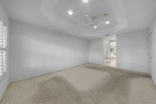 unfurnished room featuring light carpet, ceiling fan, and a raised ceiling