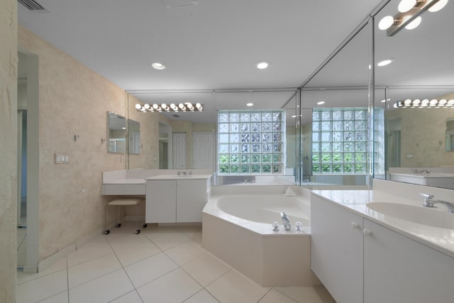 bathroom featuring tiled tub, vanity, and tile patterned flooring