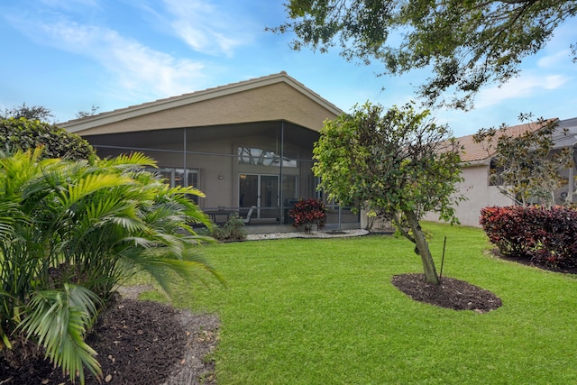 rear view of property featuring a sunroom and a yard