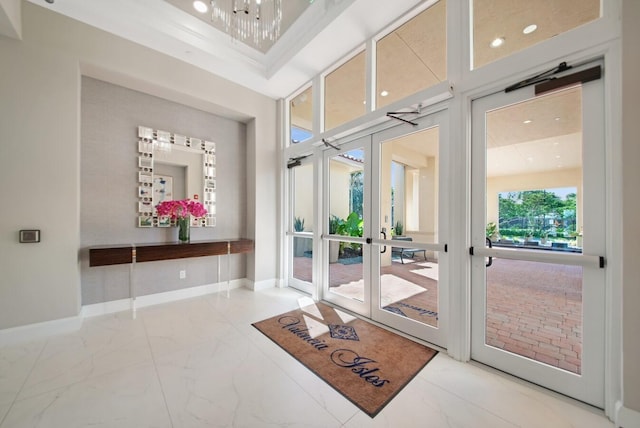 interior space featuring a high ceiling, a chandelier, ornamental molding, and french doors