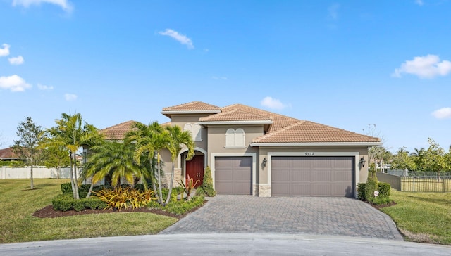 mediterranean / spanish home featuring a garage and a front lawn