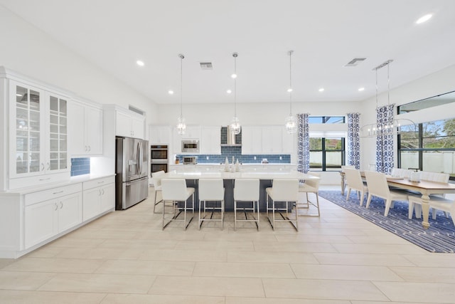 kitchen featuring white cabinets, appliances with stainless steel finishes, and pendant lighting