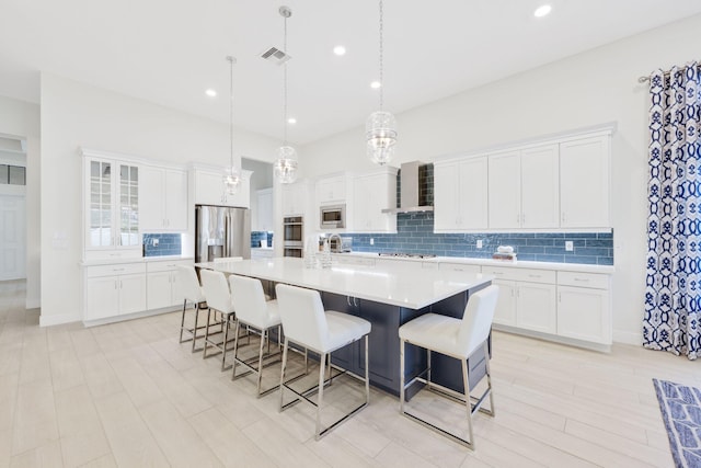 kitchen featuring white cabinets, appliances with stainless steel finishes, and wall chimney exhaust hood