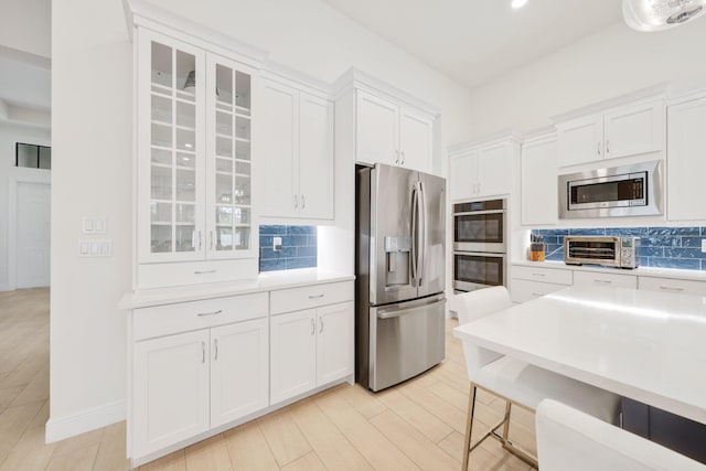 kitchen featuring backsplash, white cabinets, and appliances with stainless steel finishes