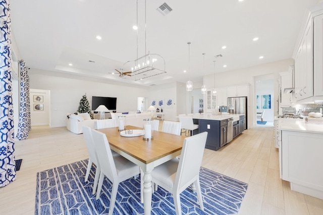 dining room with light hardwood / wood-style floors and a tray ceiling