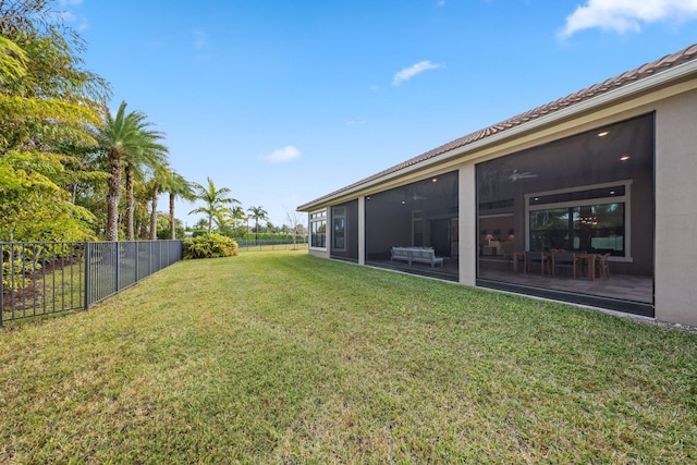 view of yard featuring a sunroom and ceiling fan