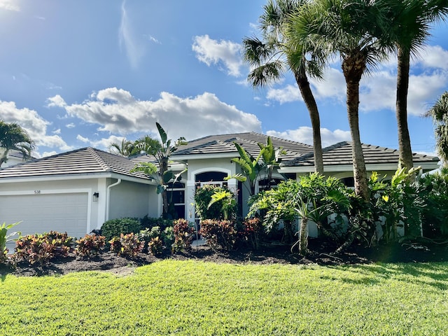 single story home with a garage, a tile roof, a front lawn, and stucco siding