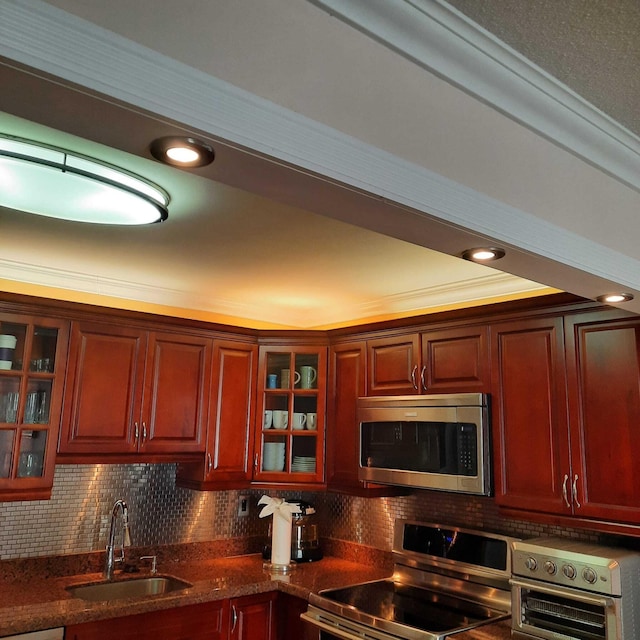 kitchen with sink, stainless steel appliances, backsplash, crown molding, and dark stone counters