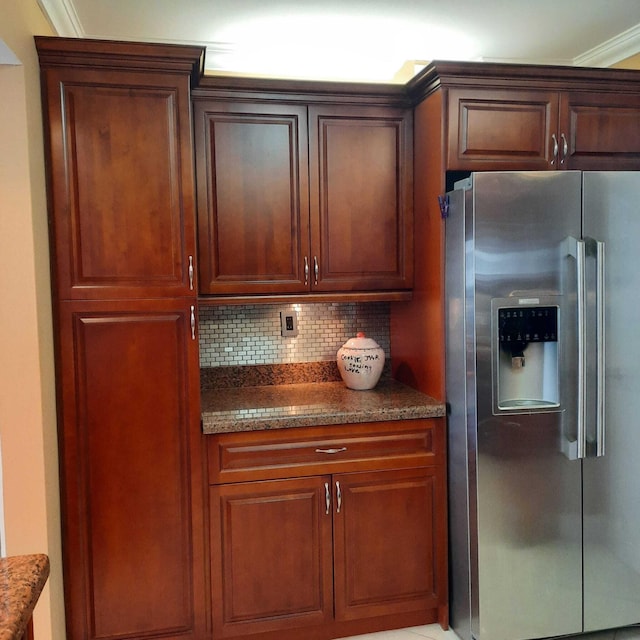 kitchen featuring stainless steel fridge with ice dispenser, backsplash, dark stone counters, and ornamental molding