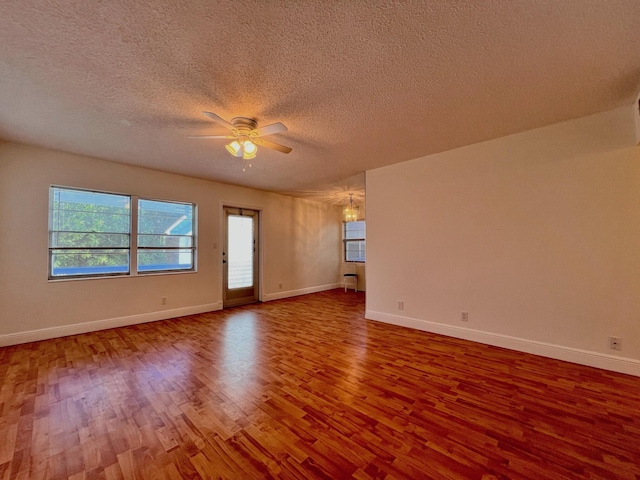 unfurnished room featuring ceiling fan with notable chandelier, a textured ceiling, and hardwood / wood-style flooring