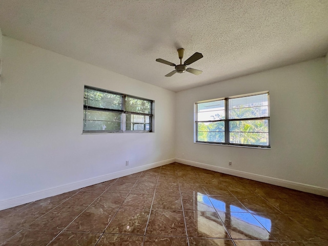 unfurnished room featuring a textured ceiling, dark tile patterned flooring, and ceiling fan