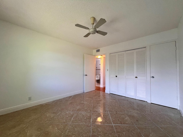 unfurnished bedroom with ceiling fan, a closet, dark tile patterned floors, and a textured ceiling