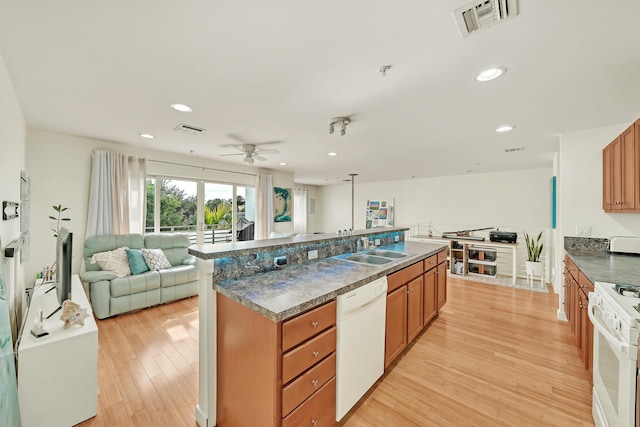 kitchen with white appliances, sink, light hardwood / wood-style flooring, ceiling fan, and a large island