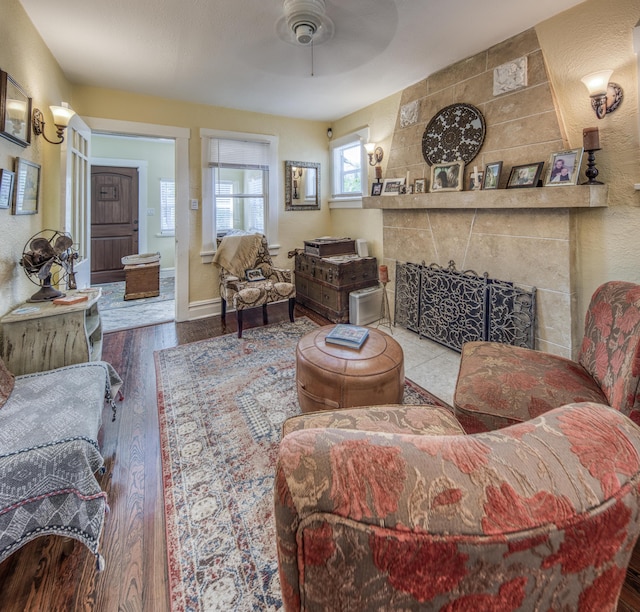 living room featuring wood-type flooring, ceiling fan, and a tiled fireplace