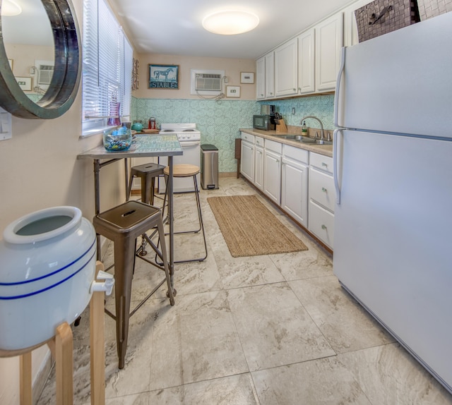 kitchen featuring white refrigerator, an AC wall unit, sink, tile walls, and white cabinetry