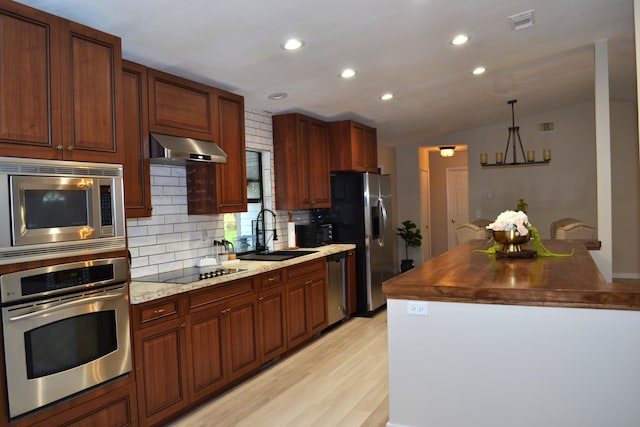 kitchen with backsplash, ventilation hood, sink, vaulted ceiling, and stainless steel appliances