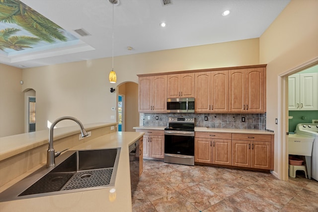 kitchen with sink, decorative backsplash, appliances with stainless steel finishes, decorative light fixtures, and washer / dryer