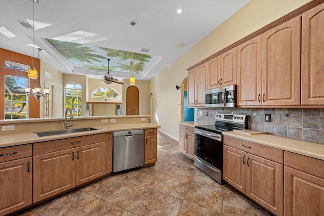 kitchen with sink, decorative light fixtures, decorative backsplash, ceiling fan with notable chandelier, and appliances with stainless steel finishes