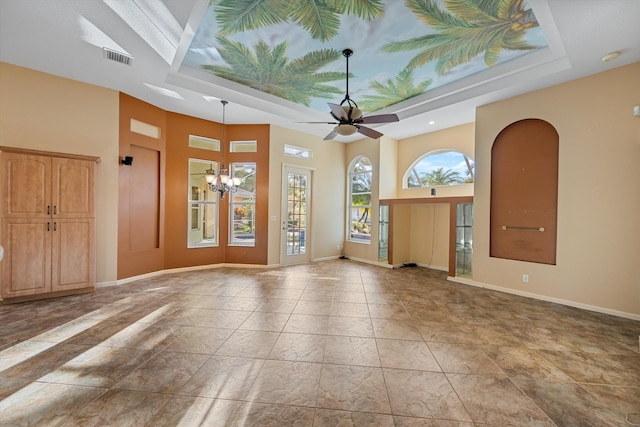 empty room featuring ceiling fan with notable chandelier and a tray ceiling