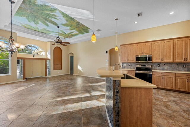 kitchen with decorative backsplash, appliances with stainless steel finishes, ceiling fan with notable chandelier, sink, and hanging light fixtures