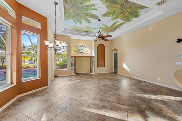 interior space featuring ceiling fan with notable chandelier and a tray ceiling