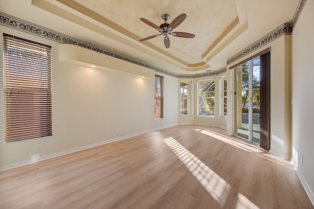 spare room with light hardwood / wood-style flooring, a raised ceiling, and ceiling fan