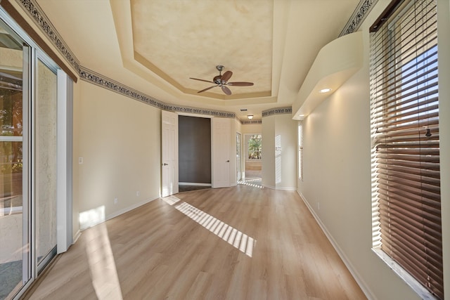 unfurnished room featuring light hardwood / wood-style floors, ceiling fan, and a tray ceiling