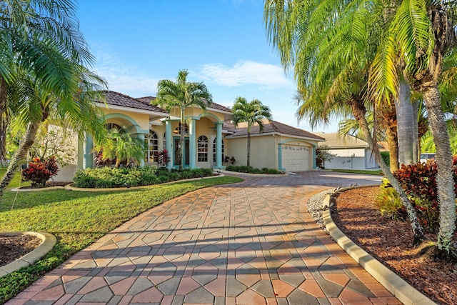 mediterranean / spanish house with a garage and a front lawn