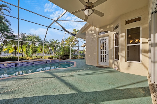 view of swimming pool with ceiling fan, a patio area, and glass enclosure