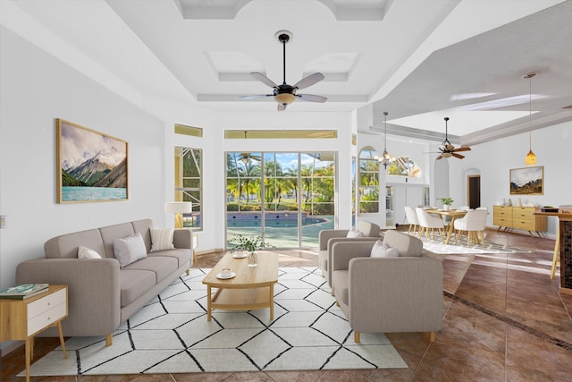 living room featuring ceiling fan, a raised ceiling, and light tile patterned floors