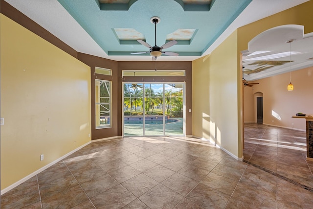 spare room with a tray ceiling and ceiling fan