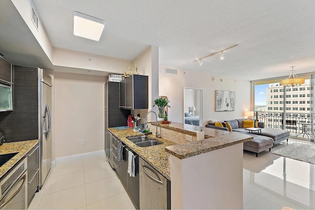 kitchen featuring floor to ceiling windows, dark stone counters, a textured ceiling, stainless steel appliances, and sink