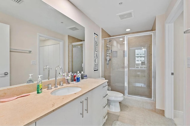 bathroom featuring tile patterned flooring, vanity, toilet, and a shower with door