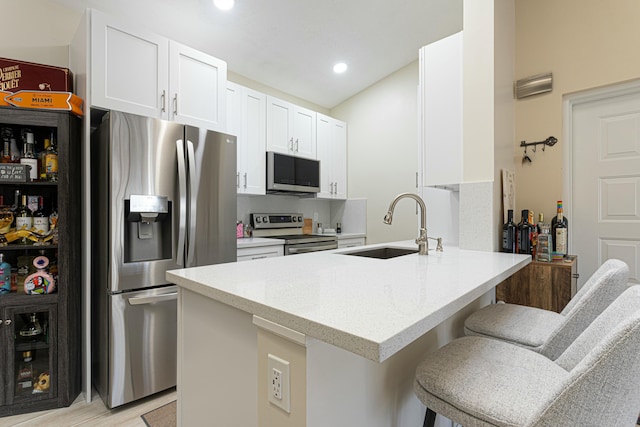 kitchen featuring white cabinets, a kitchen breakfast bar, sink, appliances with stainless steel finishes, and kitchen peninsula